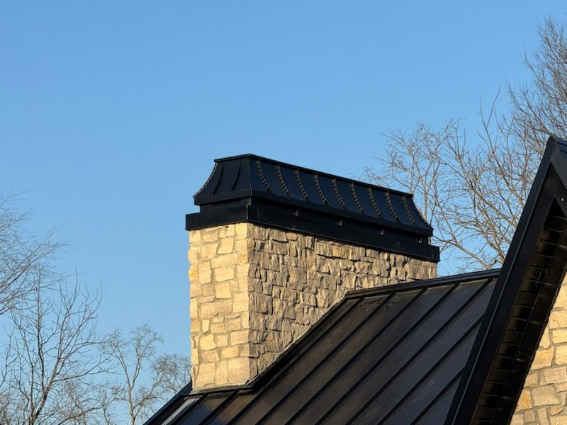 Custom Kynar aluminum chimney cap on stone masonry chimney with standing seam metal roof — Archaic Metal fabricated