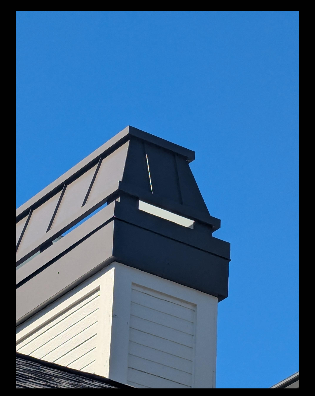 Custom Kynar aluminum chimney cap on wood-framed chase — dark charcoal finish, hand-fabricated by Archaic Metal