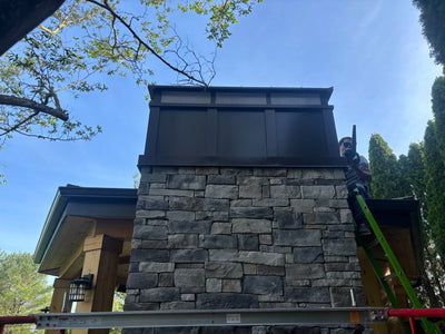 Custom board and batten extended height chimney cap installed on large stone masonry chimney
