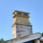 Close-up of gold anodized aluminum curved panel chimney cap on stone chimney — standing seam detail and crown molding visible, custom fabricated by Archaic Metal