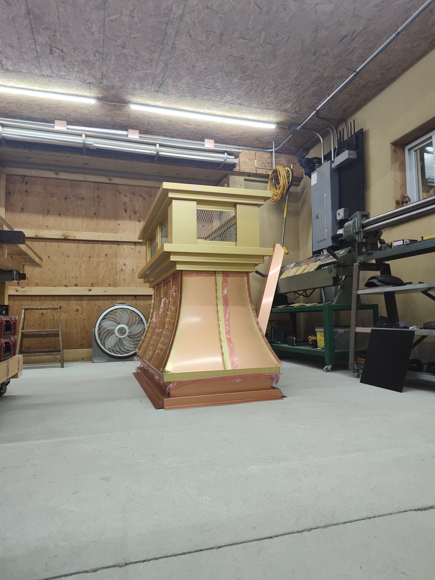 Custom curved panel anodized aluminum chimney cap on workbench during fabrication — gold crown section with stainless spark screen, Archaic Metal shop Berlin NJ