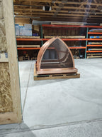 Custom arched cathedral chimney cap in 16oz copper on a pallet — front view showing convex pointed arch form and stainless steel spark screen, fabricated by Archaic Metal in Berlin, NJ