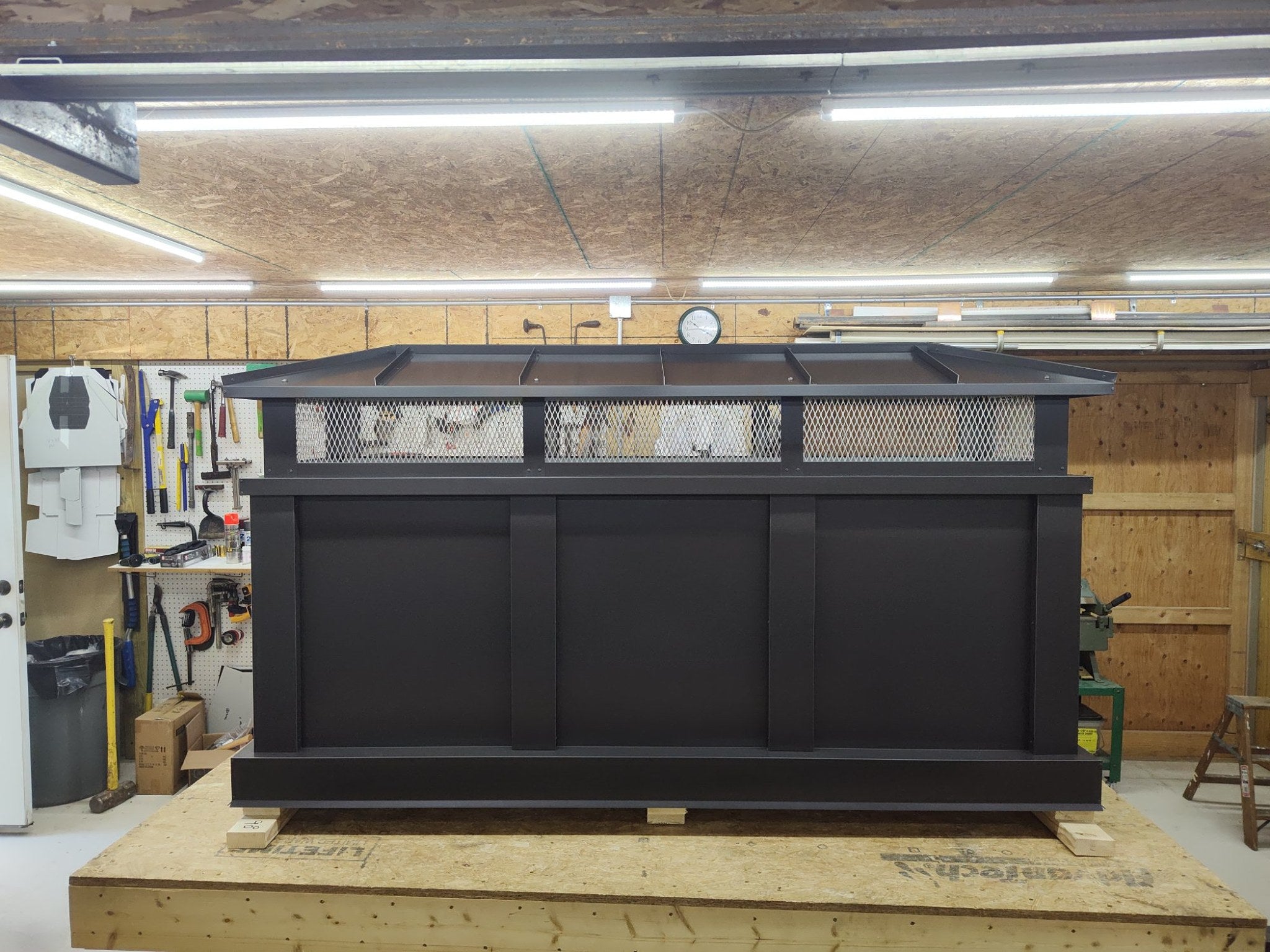 Large Kynar black board and batten extended height chimney cap, front view on workbench