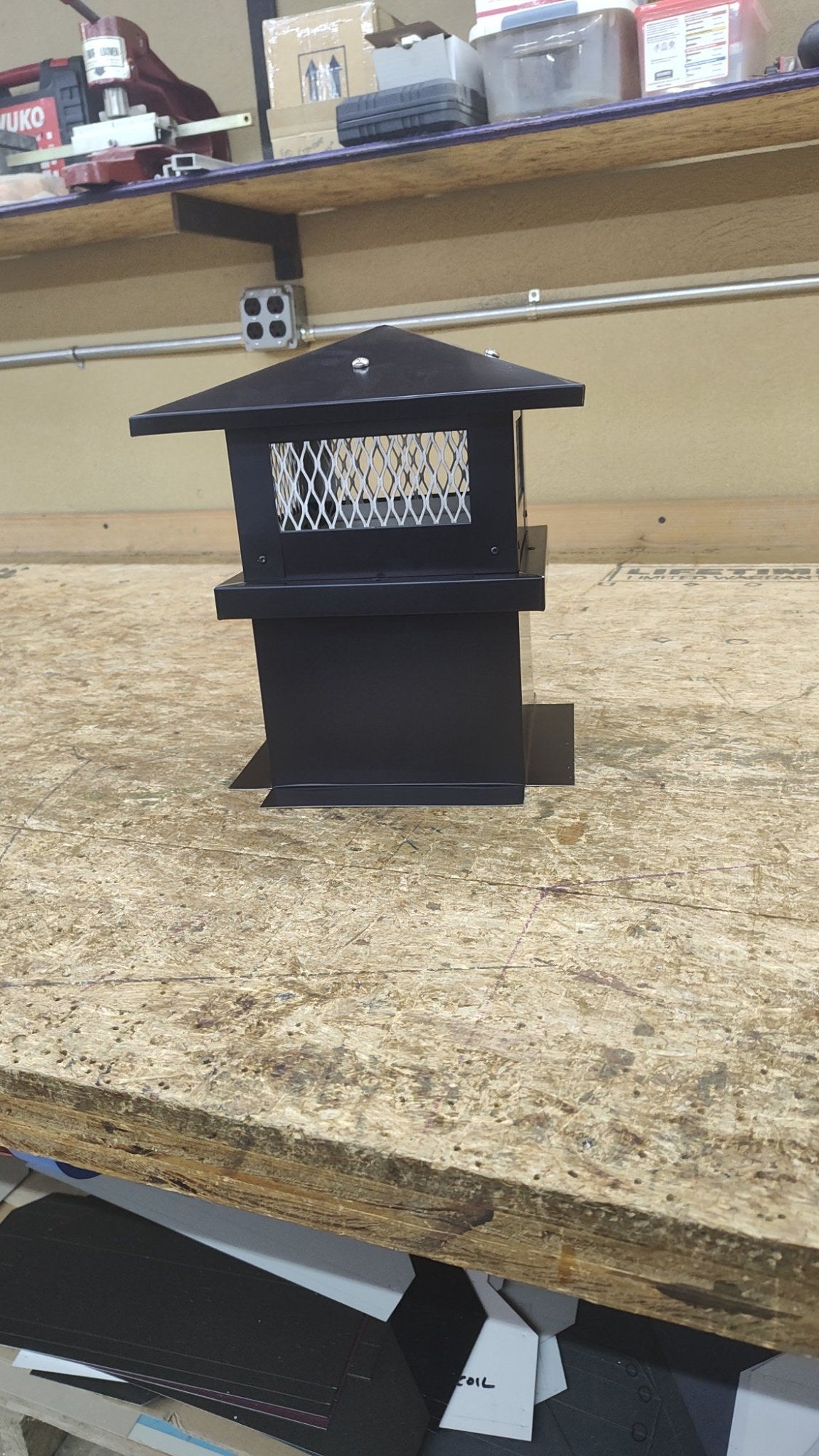 Small Kynar black board and batten chimney cap, front view on workbench