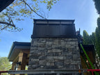 Custom board and batten extended height chimney cap installed on large stone masonry chimney