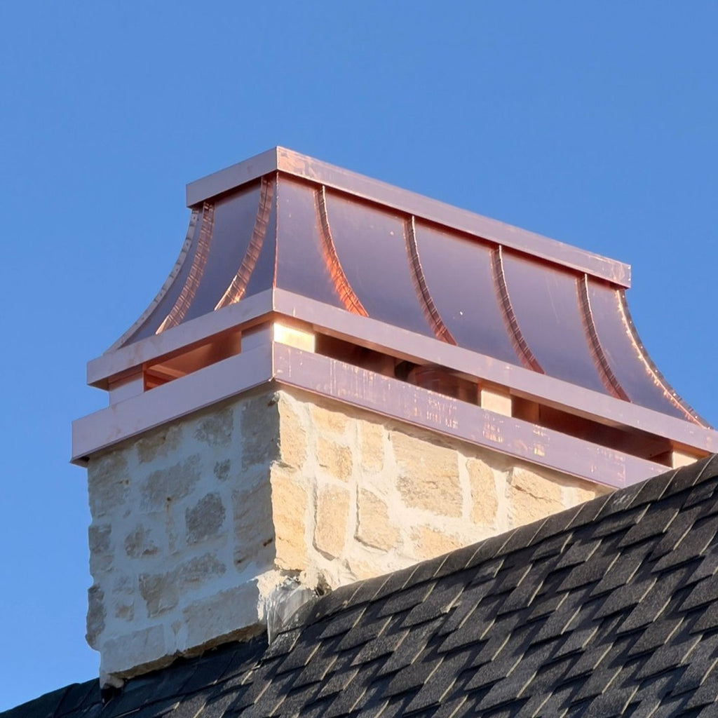 Custom copper chimney shroud with curved standing seam panels installed on stone chimney, golden hour light, Archaic Metal NJ