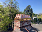 Custom copper chimney shroud with curved panel design installed on brick masonry chimney, blue sky, Archaic Metal NJ