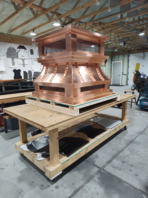 Large multi-flue copper crown top vent chimney cap on workbench, front view