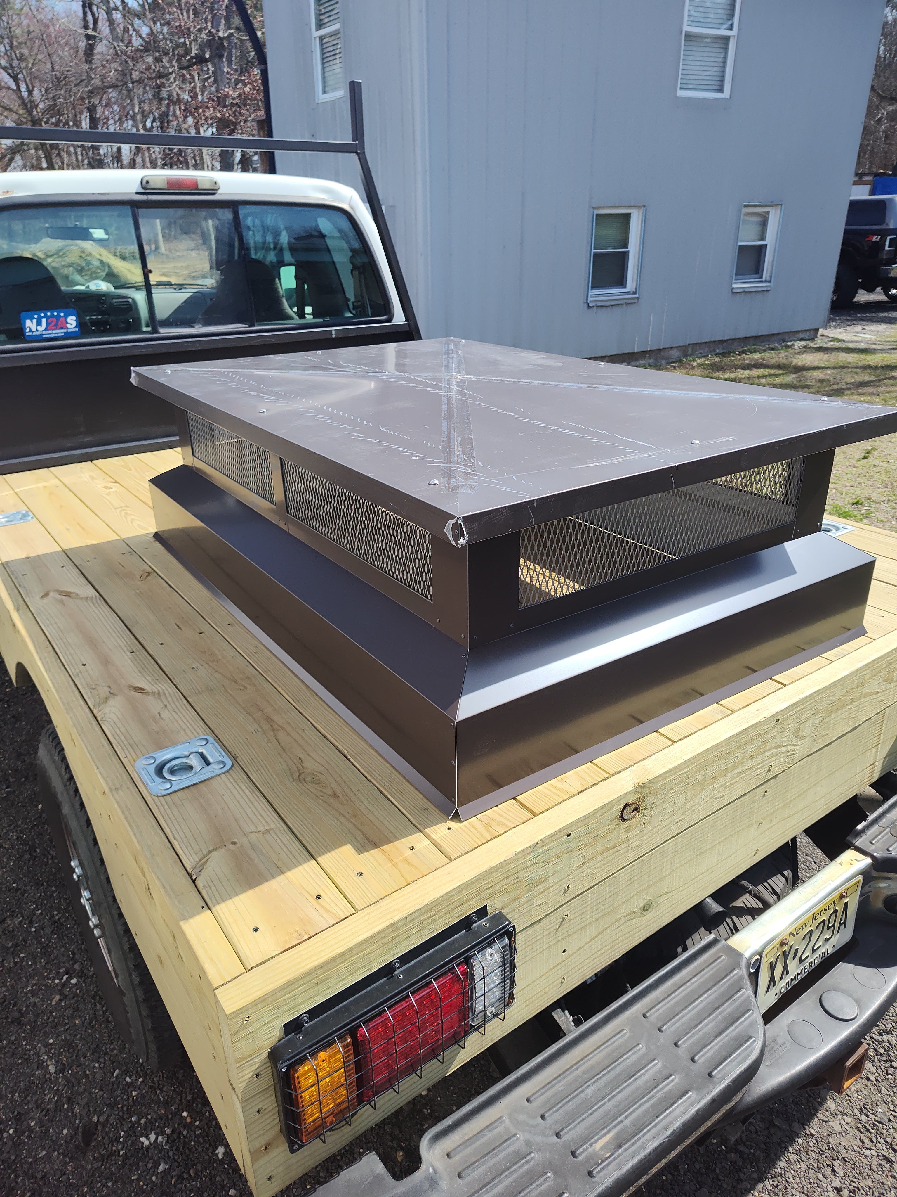 Custom multi-flue chimney cap loaded for delivery — black Kynar aluminum flat top design