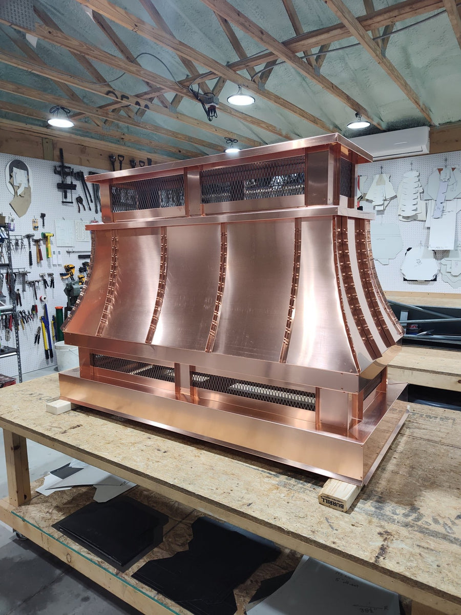 Large copper top vent curved panel chimney cap on workbench, full front view
