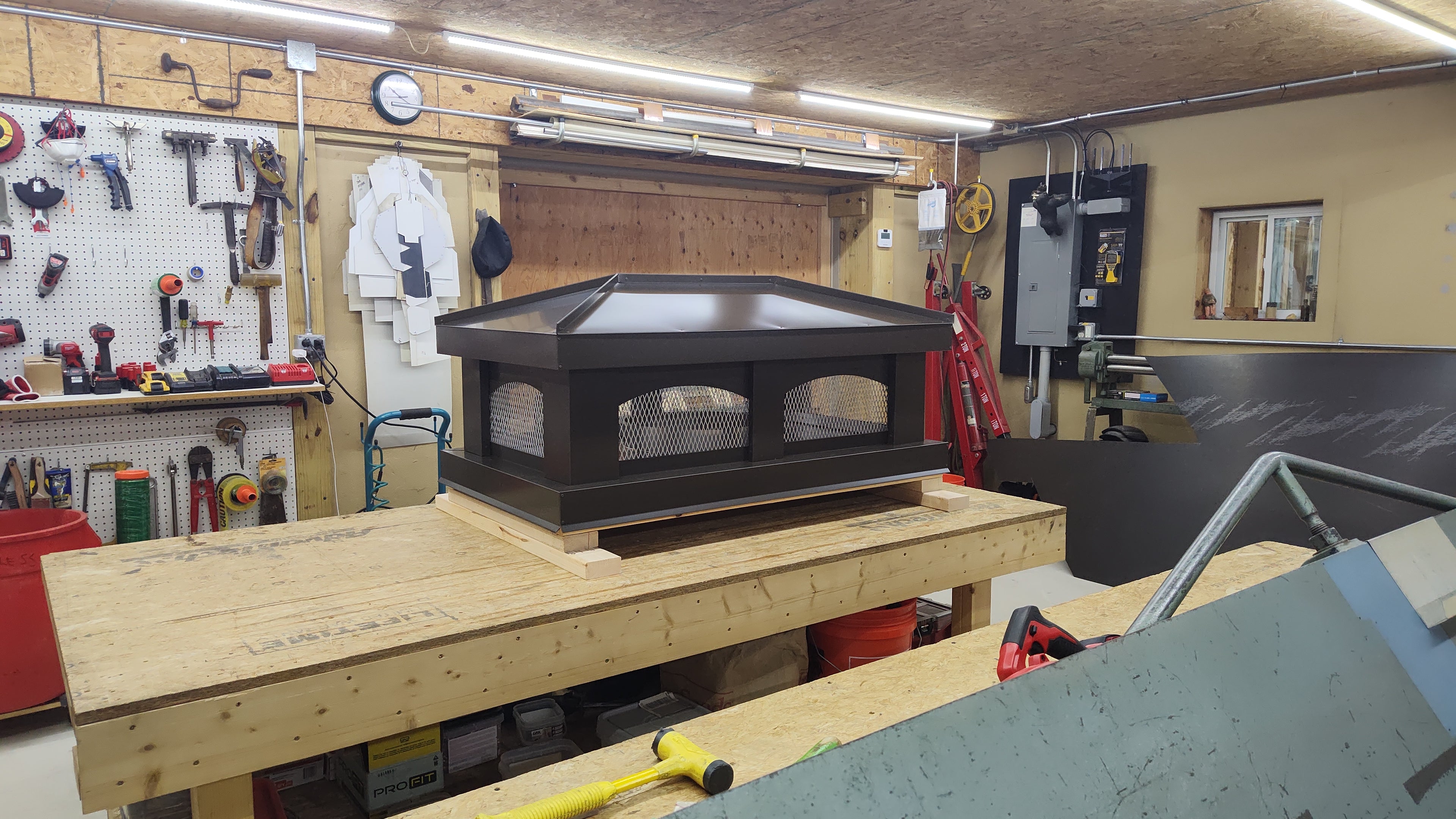 Custom hip roof chimney cap with arched openings and stainless steel spark screen

