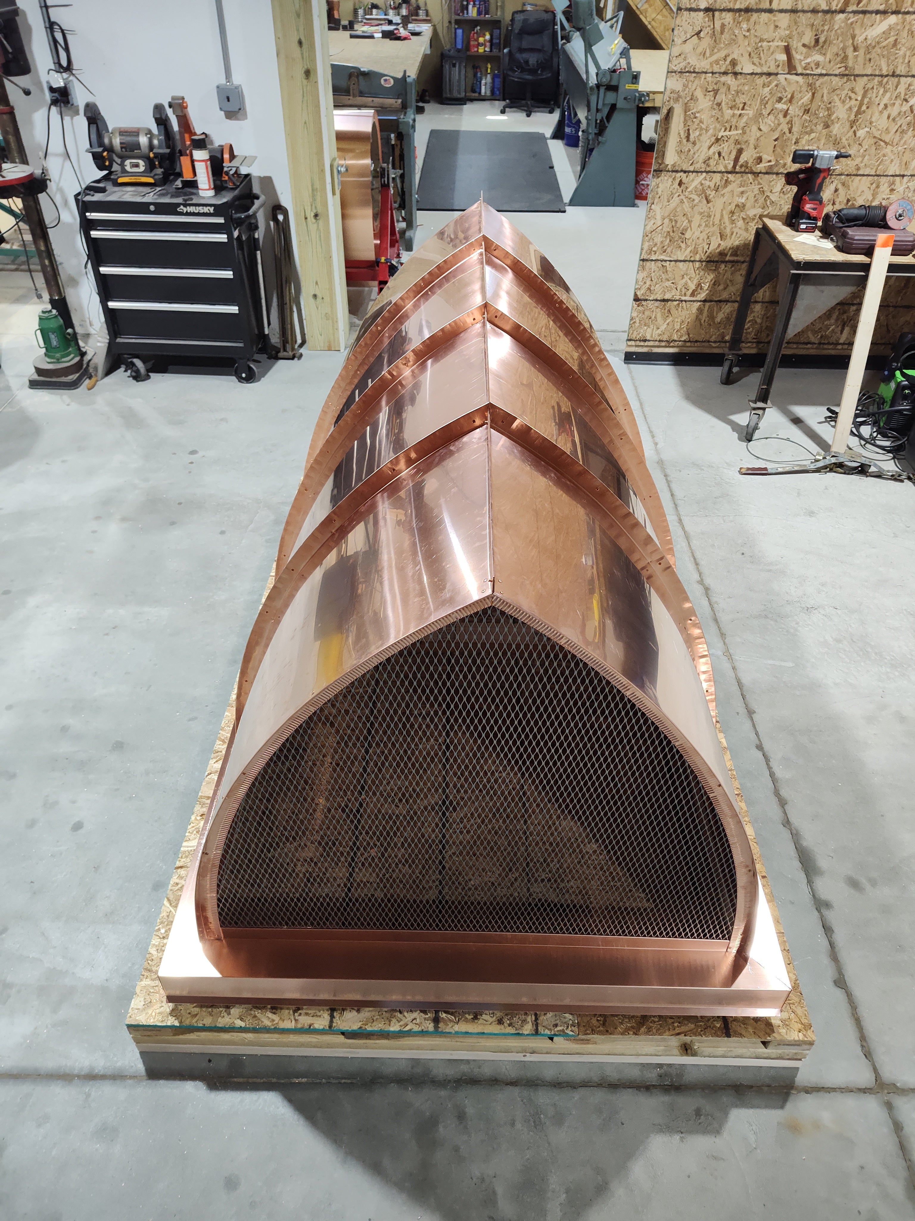 End view of large custom 16oz copper chimney cap with arched cathedral top showing standing seam panel detail, stainless steel spark screen, and side mount skirt — handcrafted by ArchaicMetal