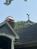 Custom copper chimney cap on brick masonry chimney with eagle weathervane above roofline — hand-fabricated by Archaic Metal