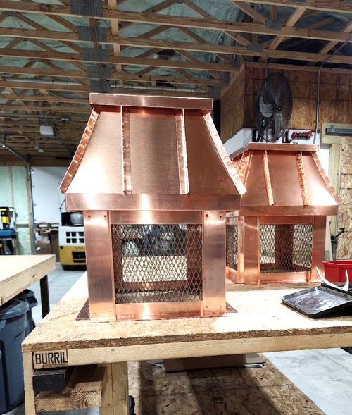 Two copper chimney caps on fabrication bench, Archaic Metal custom sheet metal shop Berlin NJ