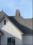 Custom copper chimney cap on stone chimney above white brick home with slate roof — hand-fabricated by Archaic Metal