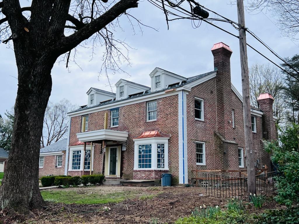 Two custom copper chimney caps installed on brick colonial home — hand-fabricated by Archaic Metal