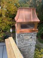 Custom copper curved panel chimney cap with stainless steel spark screen on stone masonry chimney — close-up rooftop view, hand-fabricated by Archaic Metal