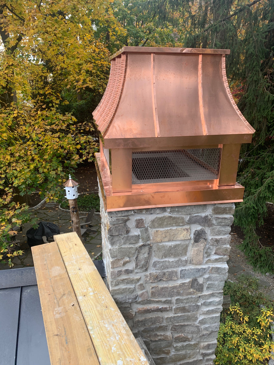 Custom copper curved panel chimney cap with stainless steel spark screen on stone masonry chimney — close-up rooftop view, hand-fabricated by Archaic Metal