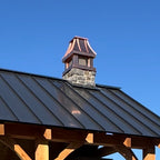 Custom copper curved panel chimney cap on stone chimney above timber frame outdoor pavilion with standing seam roof — hand-fabricated by Archaic Metal