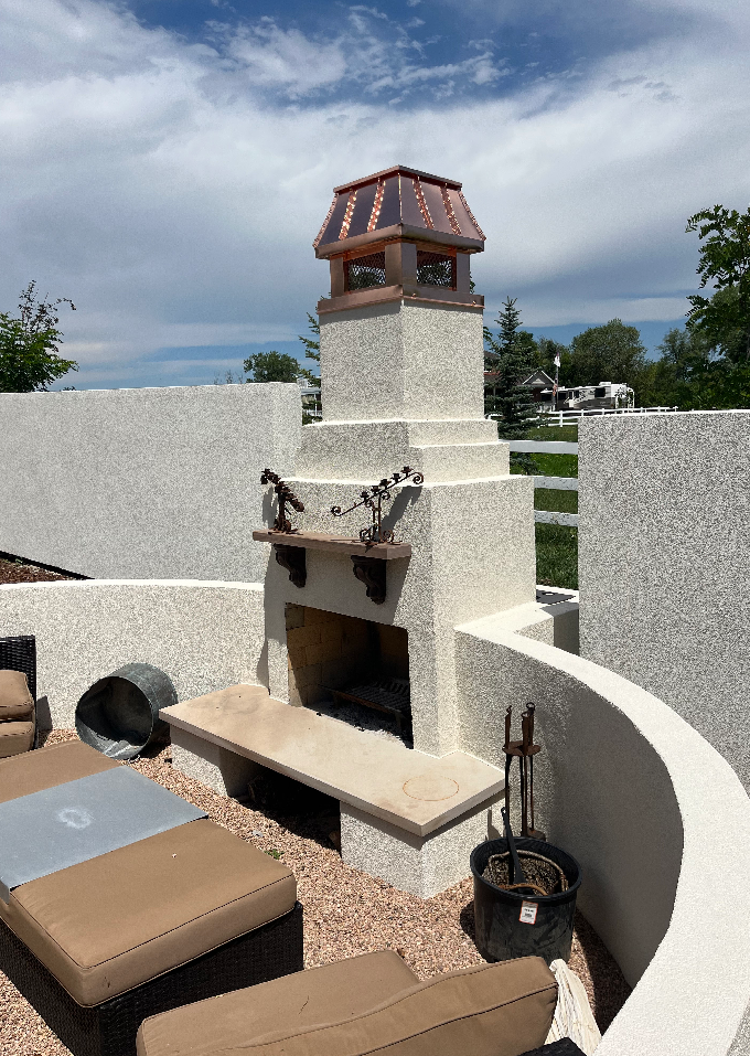 Custom copper curved panel chimney cap on stucco outdoor fireplace column with curved patio seating area — hand-fabricated by Archaic Metal
