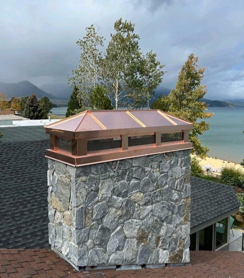 Custom copper hip and ridge chimney cap installed on stone chimney – Archaic Metal