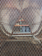 Interior detail view looking through the 18-gauge expanded stainless steel spark screen of a curved panel chimney cap — close-up showing screen mesh quality and cap base structure, fabricated by Archaic Metal in Berlin, NJ