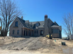 Large luxury home under construction with multiple uncapped chimneys — custom chimney caps for new builds fabricated to order by Archaic Metal