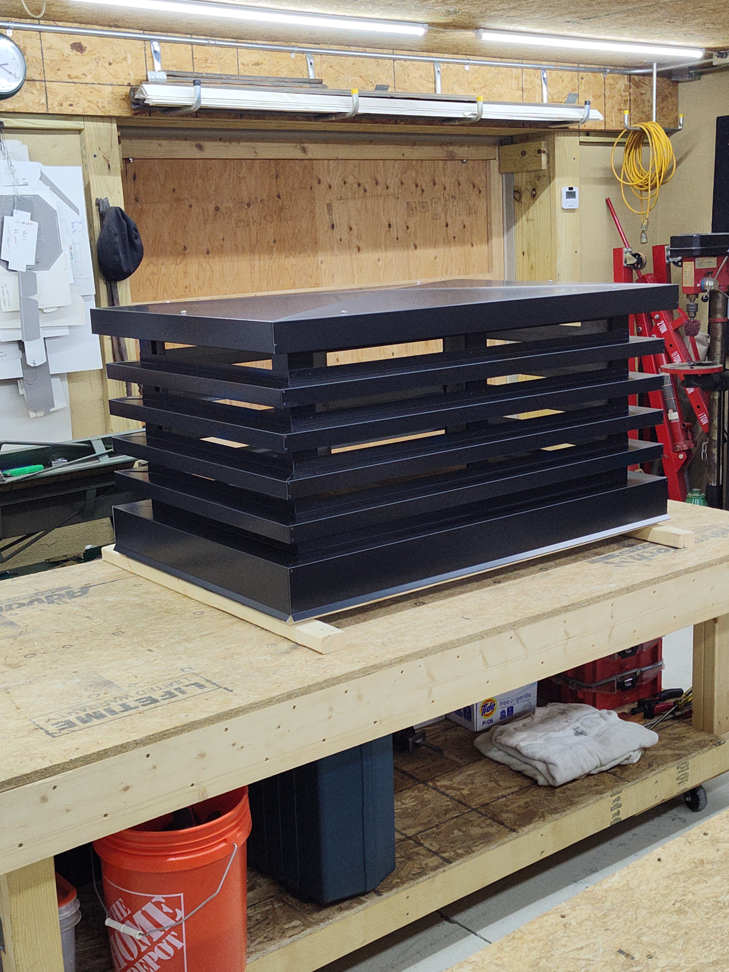 Custom louvered chimney caps stacked in workshop — mid century modern chimney shroud fabrication