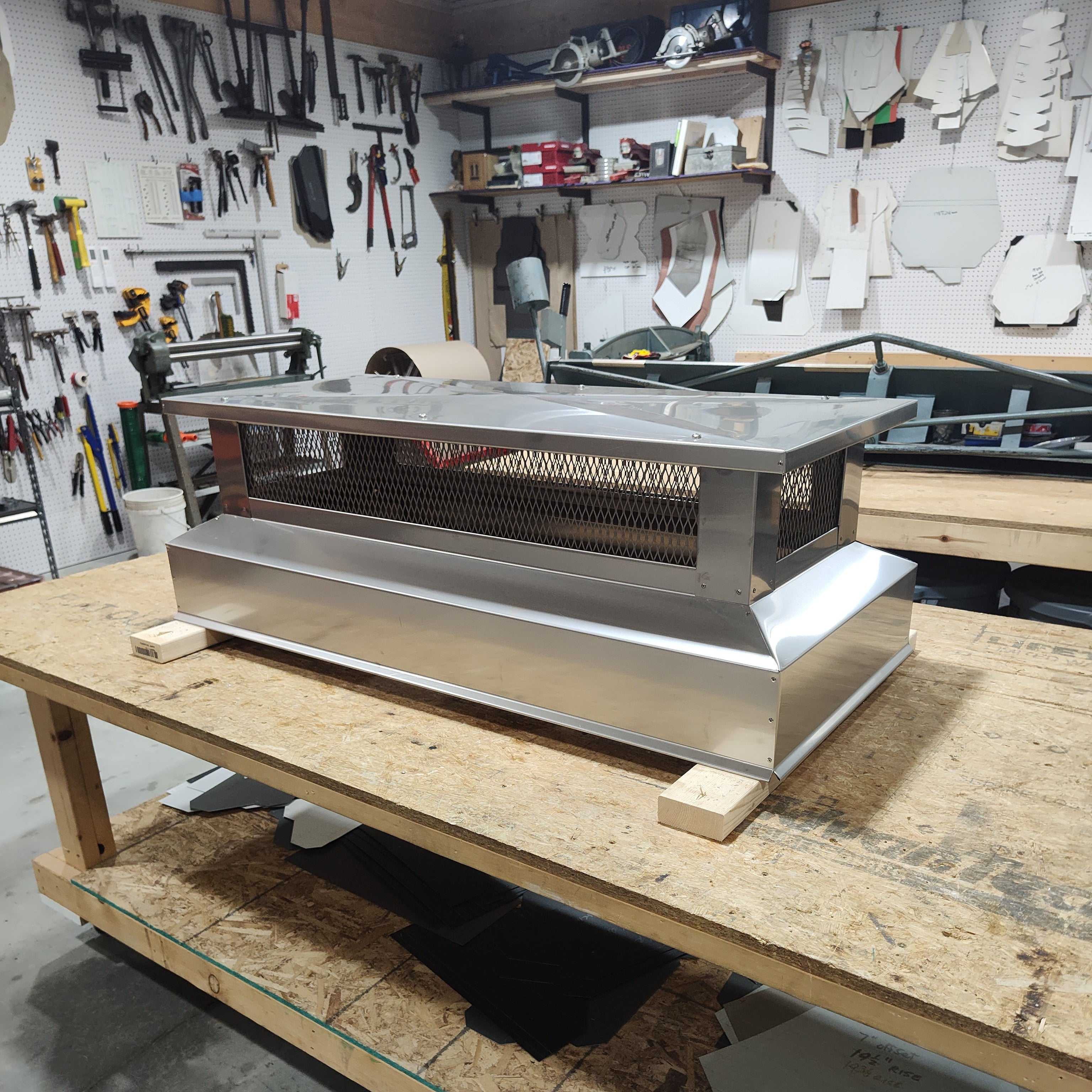 Custom stainless steel multi-flue chimney cap on fabrication workbench, handcrafted by Archaic Metal