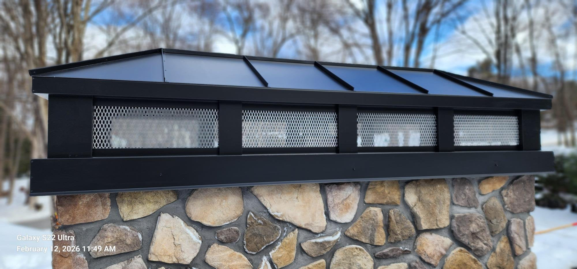 Custom black Kynar aluminum hip and ridge chimney cap installed on stone chimney — hand-fabricated by Archaic Metal, Berlin NJ