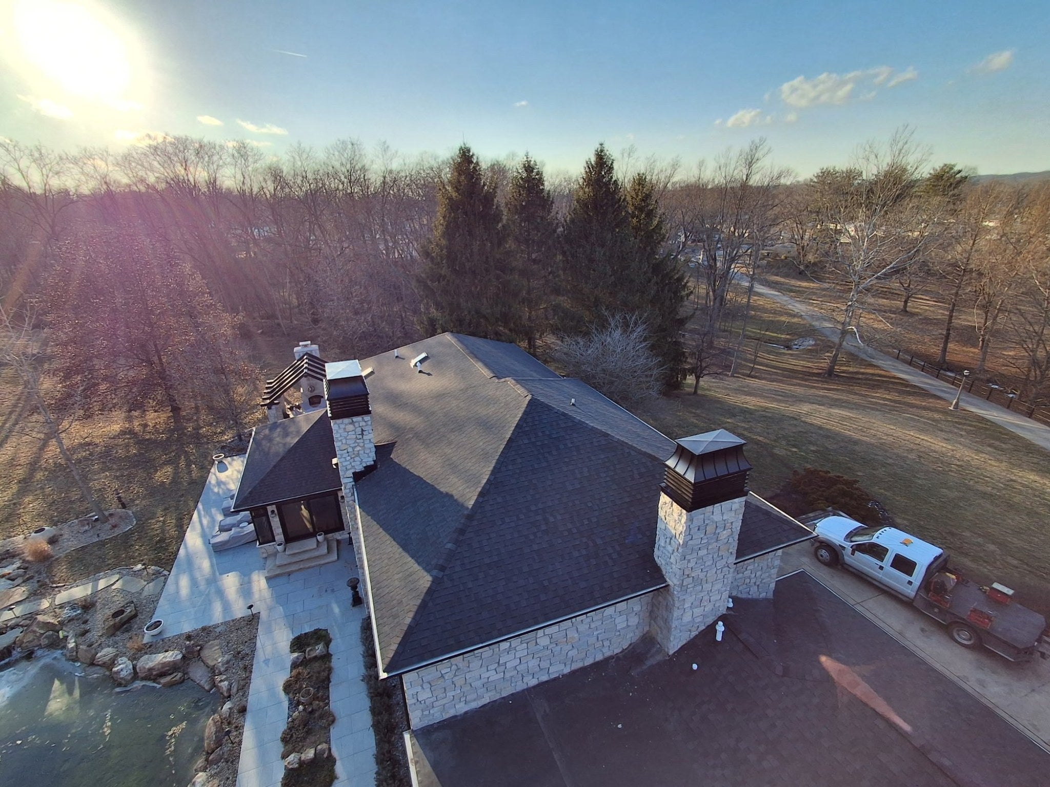 Aerial view of custom modern louvered chimney caps installed on roof of high-end stone home — black Kynar aluminum, fabricated by Archaic Metal