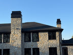 Pair of custom modern louvered chimney caps installed on stone chimneys — black Kynar aluminum, matched set fabricated by Archaic Metal
